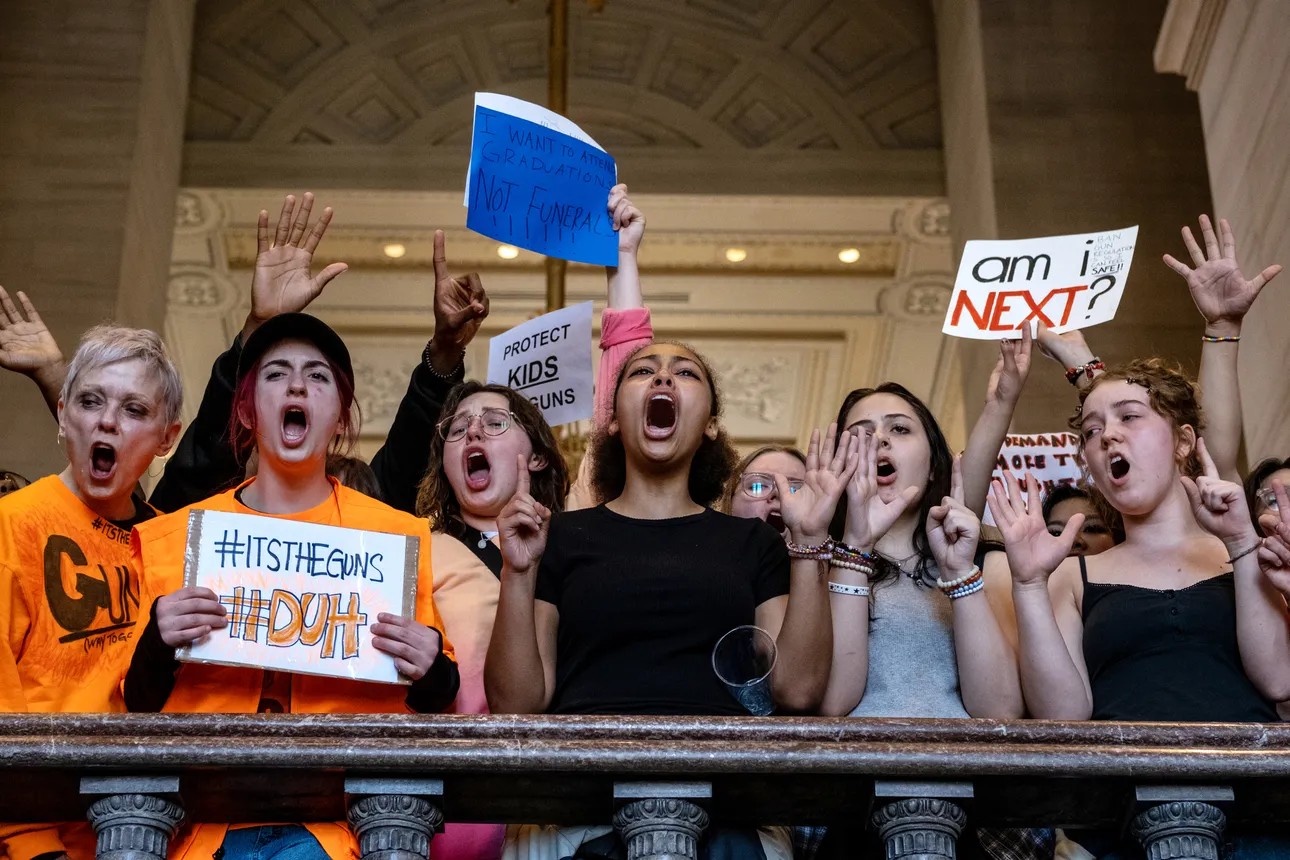 Teenage protestors hold signs and raise their arms