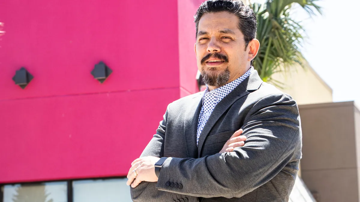 A photo of Ulyses Camacho smiling in front of a Taco Cabana restaurant.