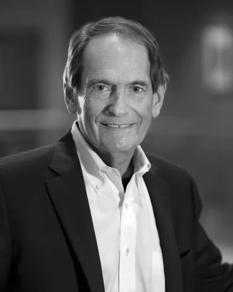 A man in a suit poses for a photograph