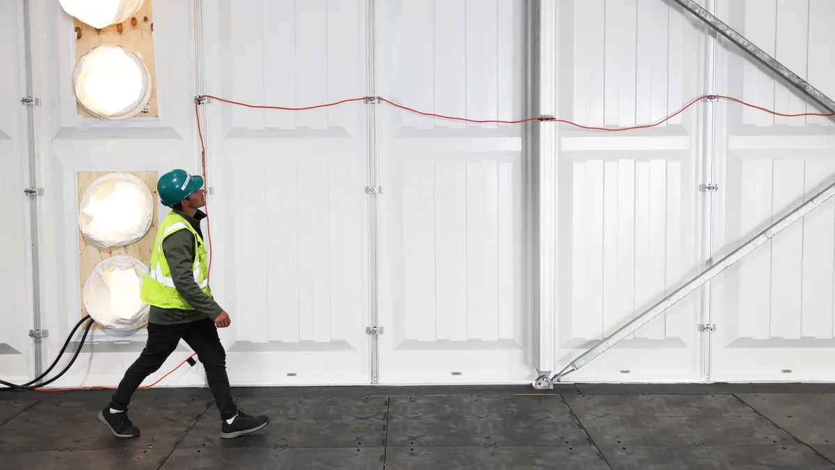 A worker walks past a temporary wall.