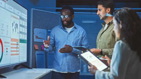 Colleagues standing , looking at a presentation on a projector