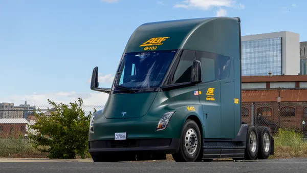 An ABF Freight Tesla Semi with a city landscape in the background.