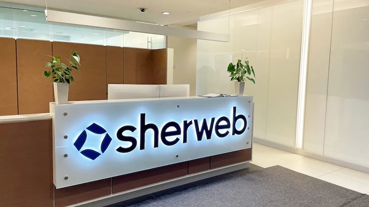 Technology company Sherweb's logo pictured on a reception desk in the lobby of a modern office building.