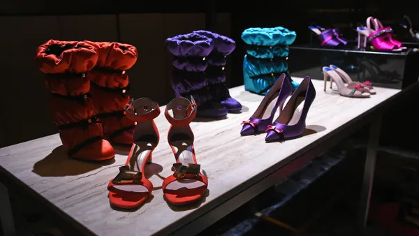 Shoes are displayed on a table under a bright light while the room is dark.