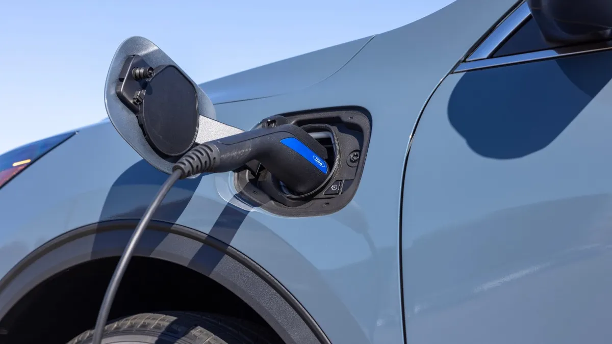 A cable shown plugged into the charging port on the left front fender of a 2023 Ford Escape hybrid SUV.