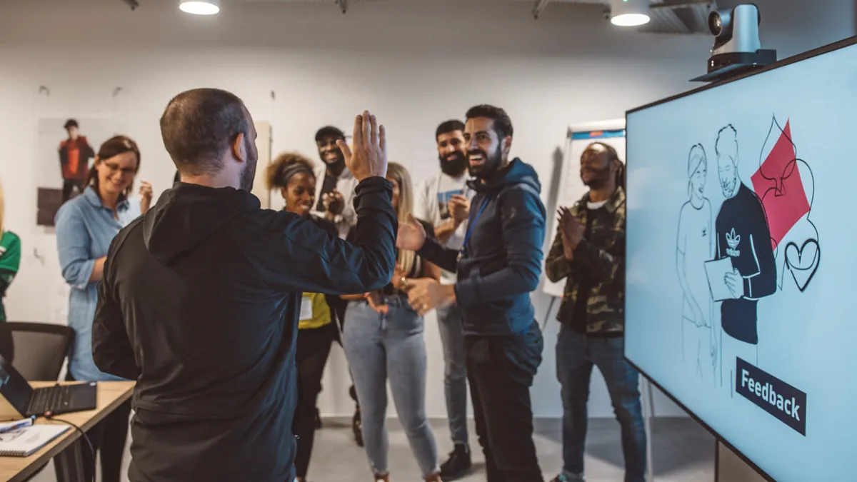 Adidas employees gather around a screen that says "Feedback."