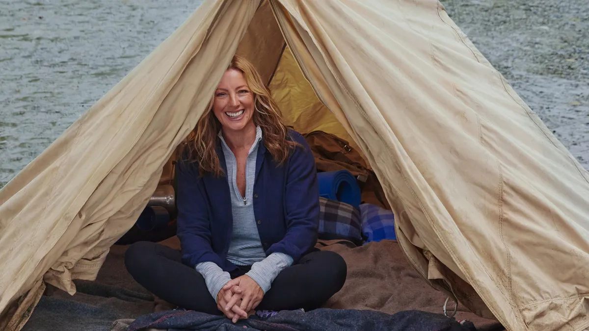 Singer Sarah McLachlan sits in a tent next to a wolf as part of Busch Light's 2023 Super Bowl commercial.