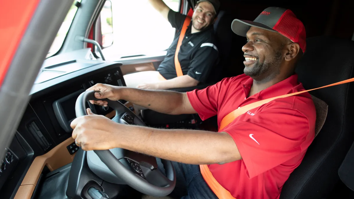 Two U.S. Xpress drivers sitting in the cab of a truck