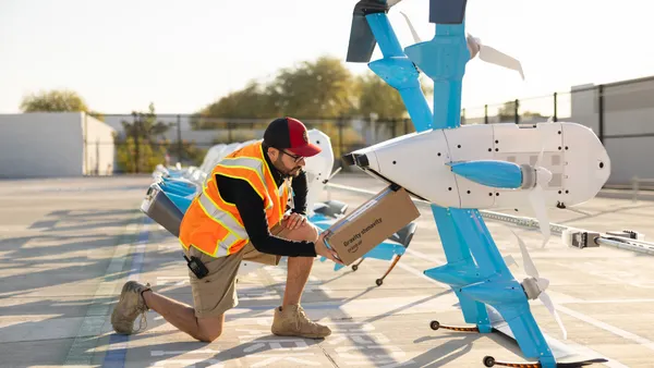 A person loads a box into a drone.