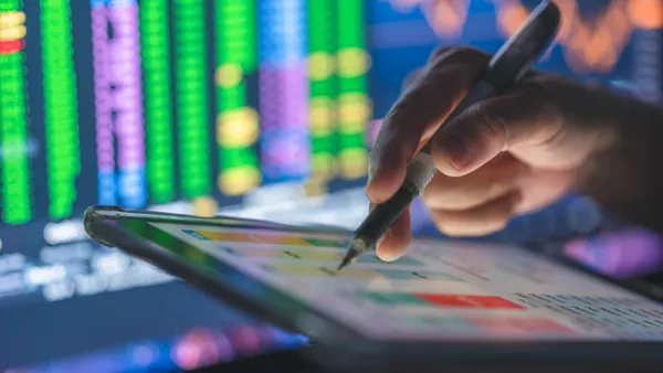 A business professional uses a tablet displaying charts and graphs.