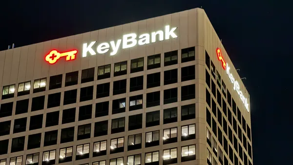 A close-up shot of the top of an office building at night shows the name "KeyBank" with a key logo.