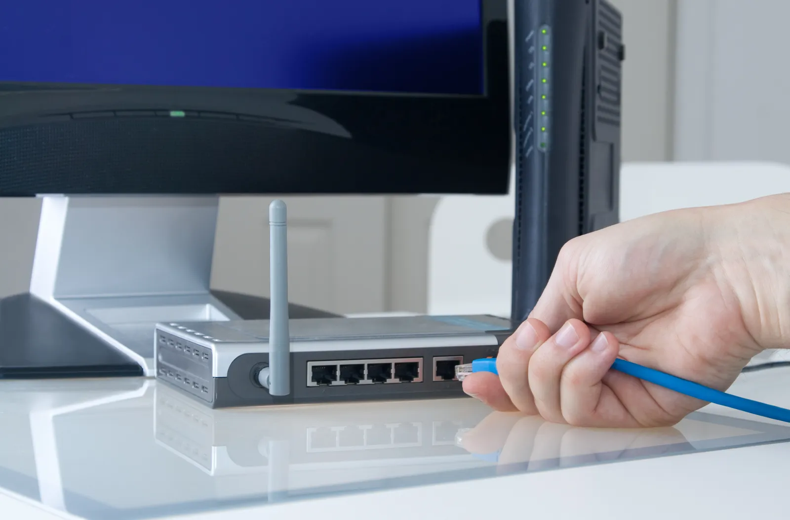 A hand plugs a cable into a router.