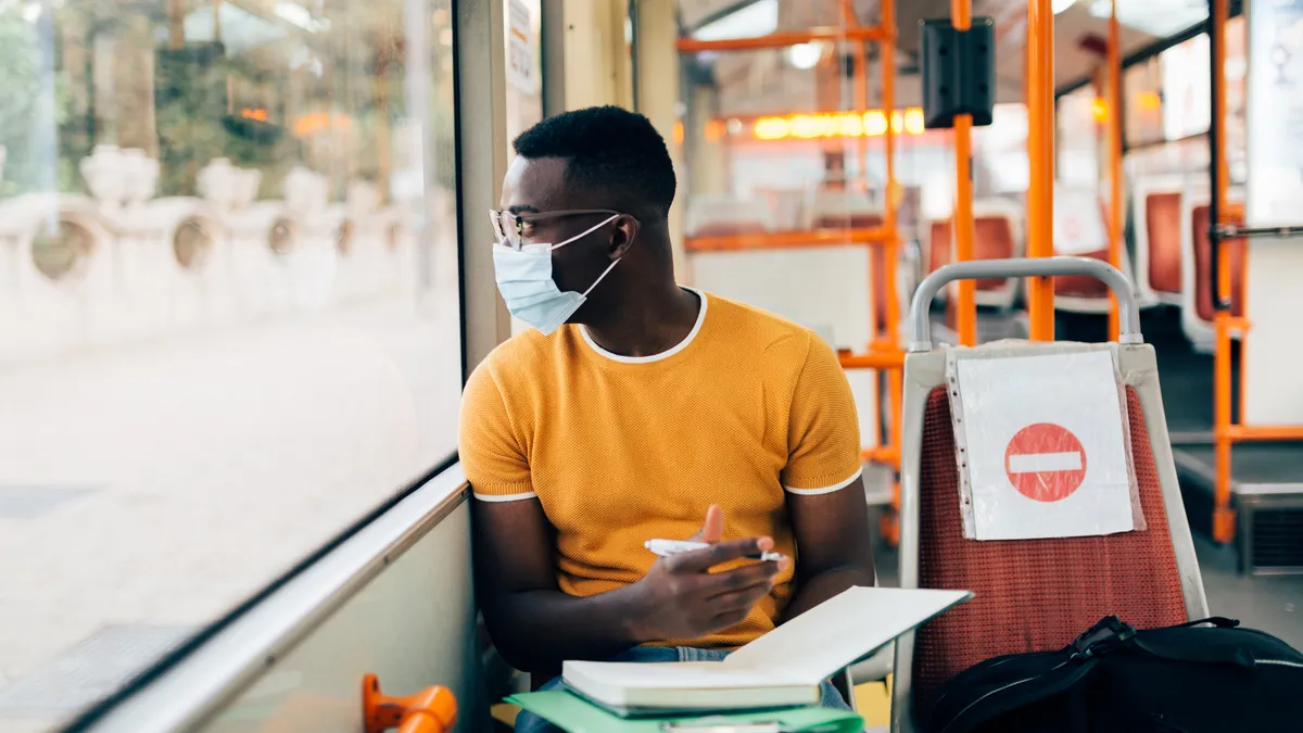 A young Black man is commuting on a bus