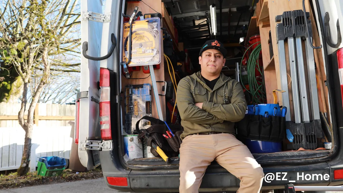 A man poses for a photograph in the back of a utility van.