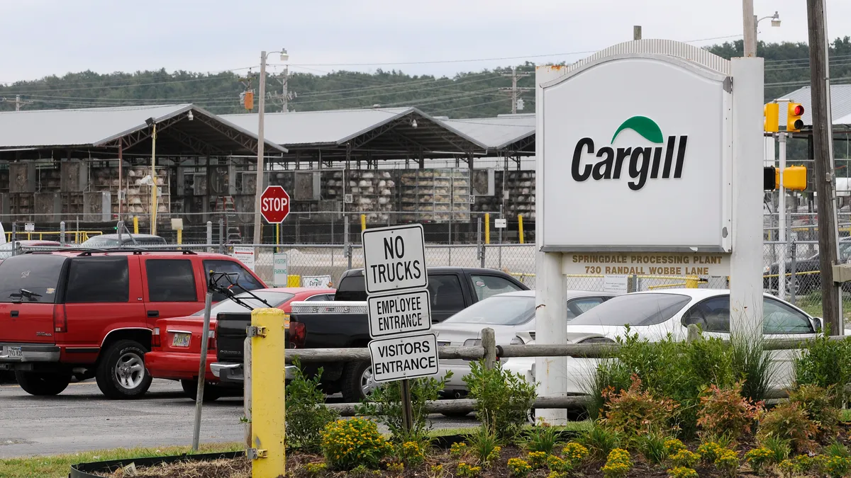 A Cargill sign is seen at the entrance of a parking lot where cars sit.