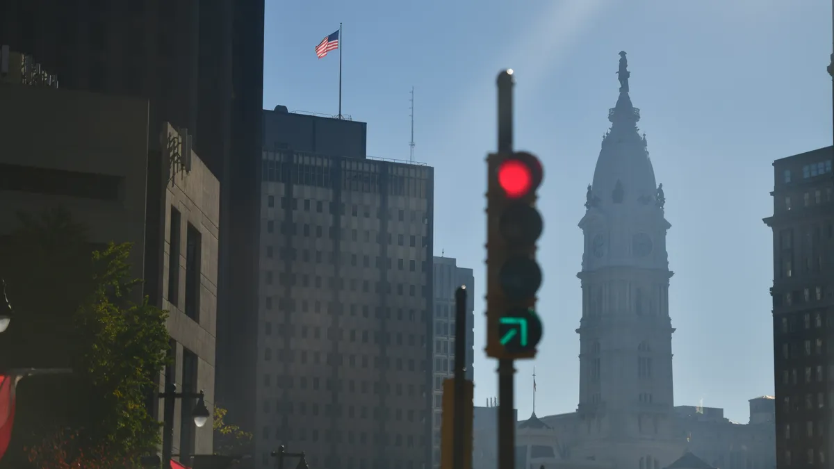 City landscape with government building in background, alongside U.S. flag and traffic light