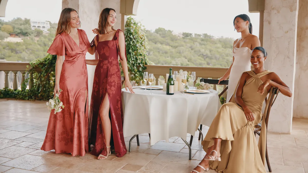 A group of people wearing Birdy Grey bridesmaid dresses gathered around a table.