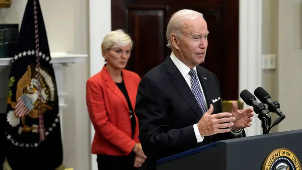 U.S. President Joe Biden speaks at a podium, with Energy Secretary Jennifer Granholm in the background.