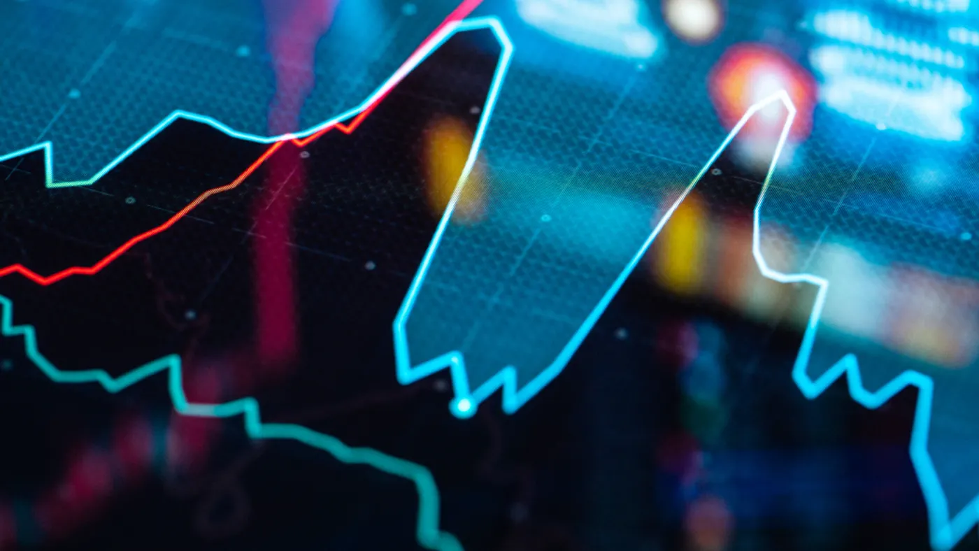 A digital graph with red and blue lines showing fluctuating data, set against a blurred, colorful background. The image conveys a sense of dynamic business analysis.