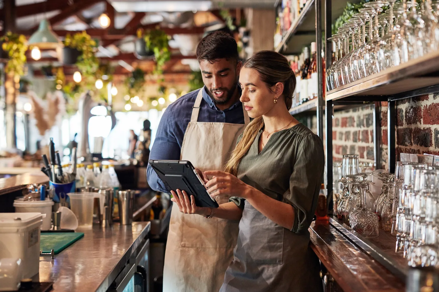 Two people looking at a digital tablet behind a bar