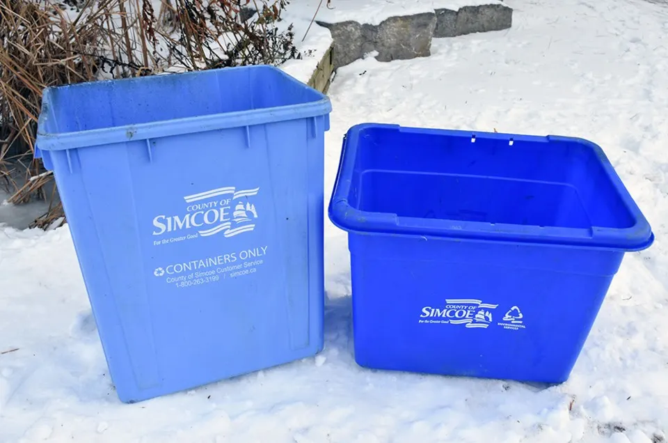 Blue recycling boxes sit in the snow