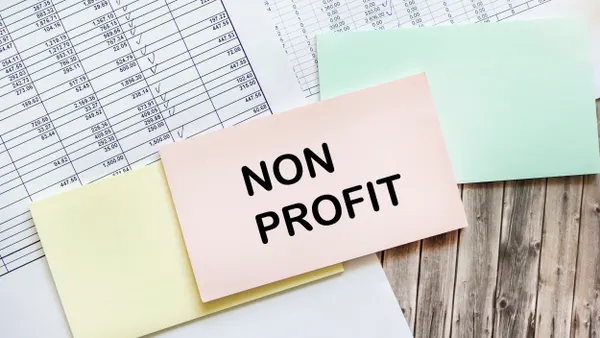 A pink sticky note with the words "Non Profit" on top of a pile of balance sheets.