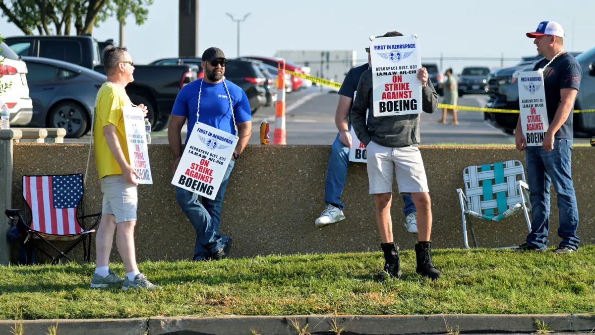 Five people carrying signs that say IAM District 837 is striking against Boeing.