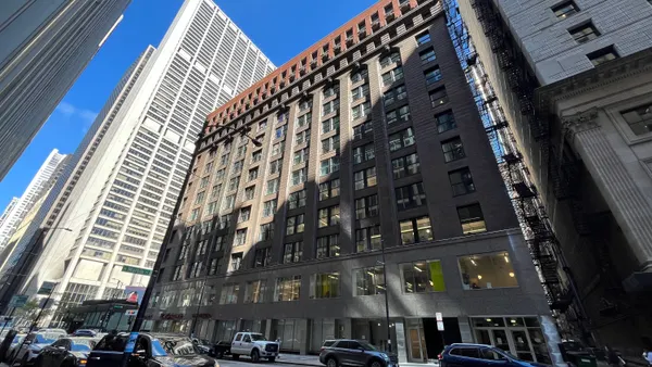 A brick high-rise in a downtown area with a blue sky overhead.