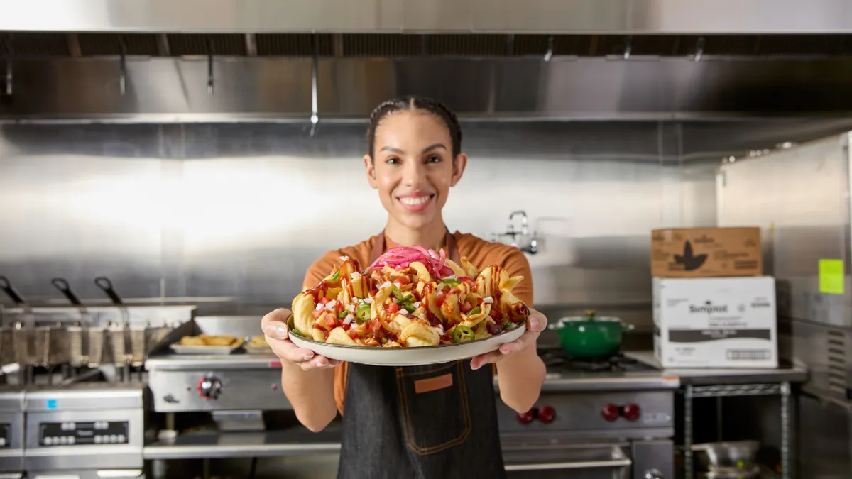 A person smiling with a plate of food in a industrial kitchen