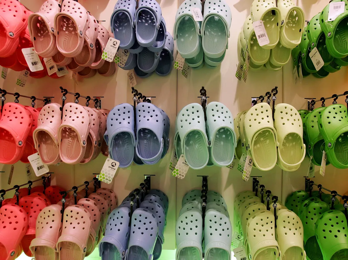 Multiple rows of Crocs in different colors are seen in a store.