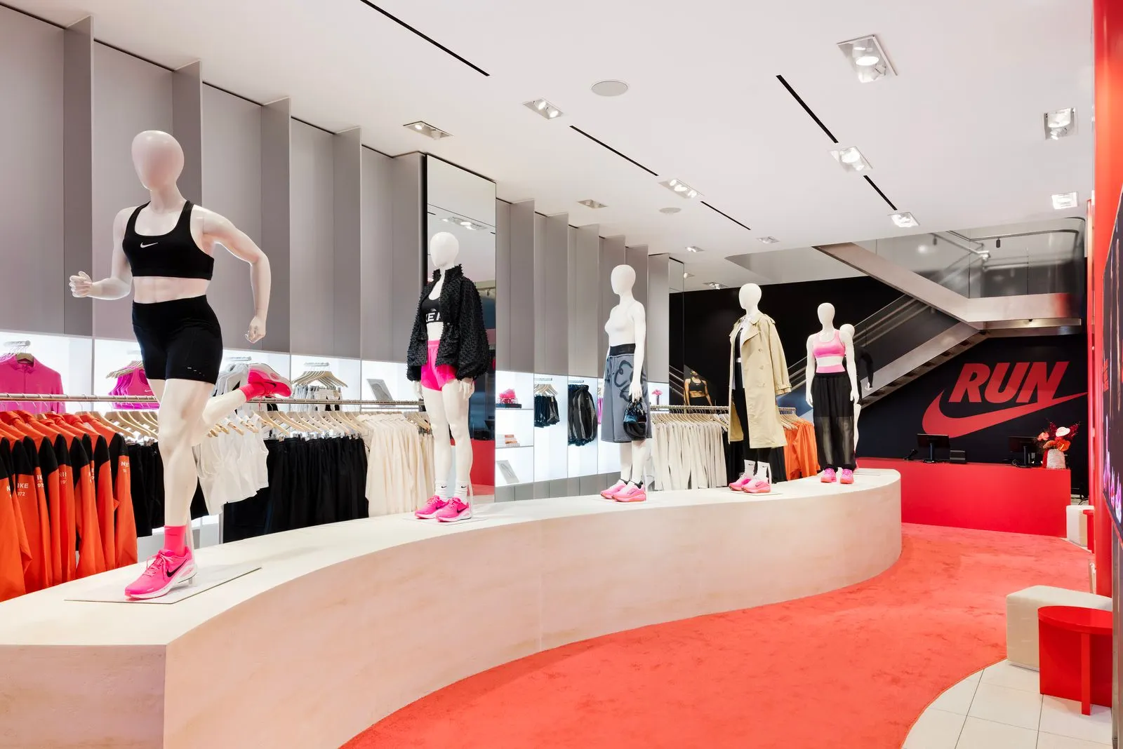 A line of mannequins in running apparel above a red carpet and a Nike logo.