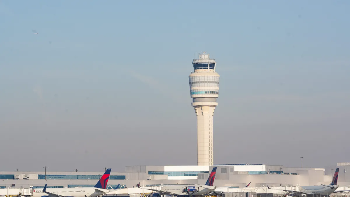 Planes go past the air traffic control tower as people travel through Hartsfield-Jackson Atlanta International Airport