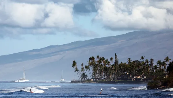 A surfer rides a wave in the distance