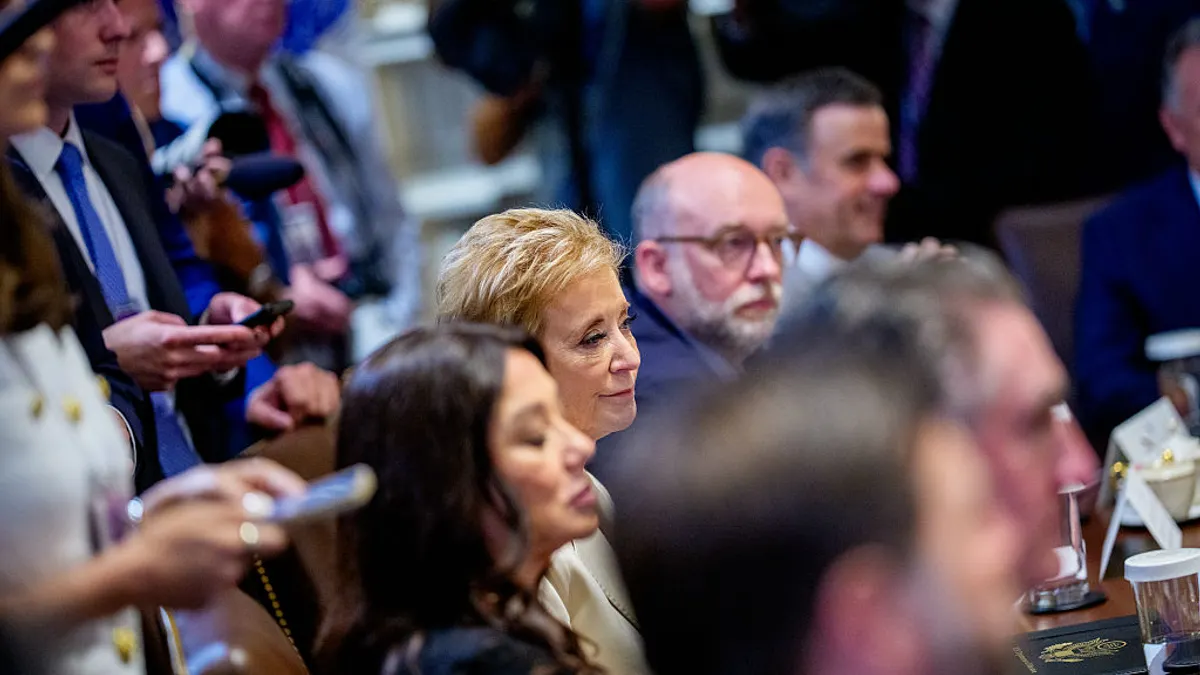 Several people are seated at a table. The camera focuses in on two people in the center of the photo.