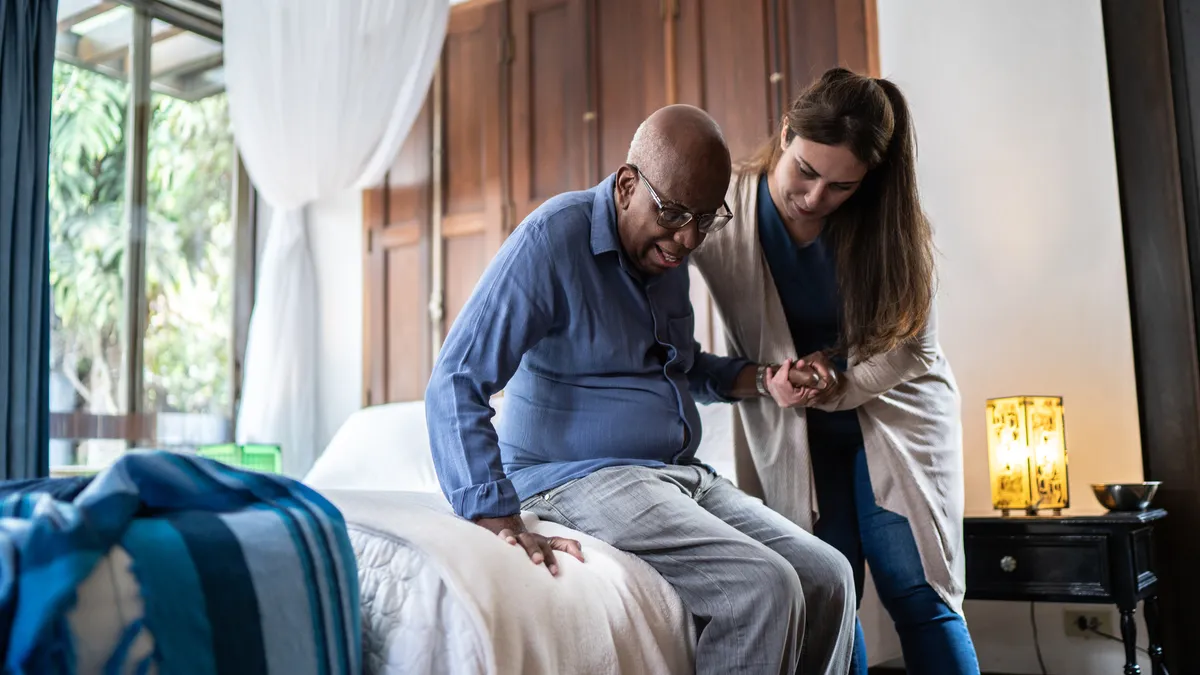 A home health aide assists a man.