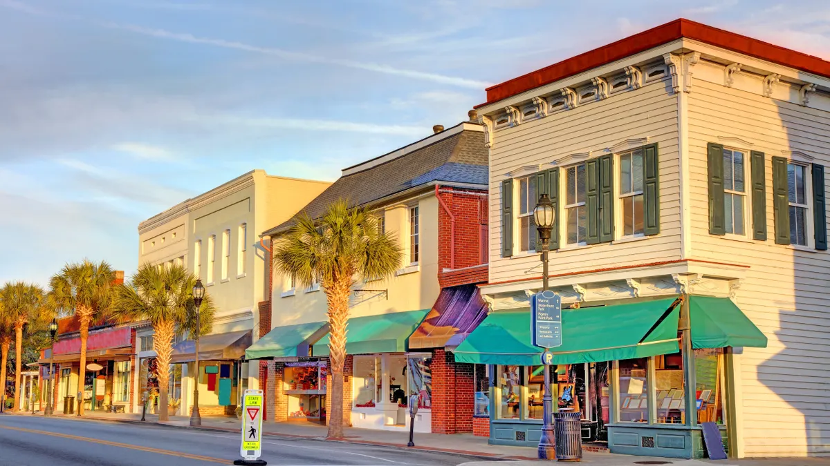 Two-story buildings with awnings line a street.