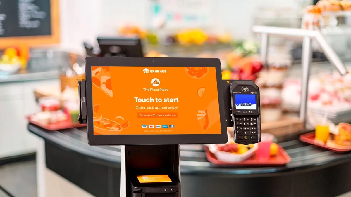 A photograph of a Grubhub kiosk with a buffet line in the background. These kiosks are used for campus dining programs.