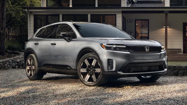 A 2024 Honda Prologue electric SUV parked in from of a house on a wooded lot.