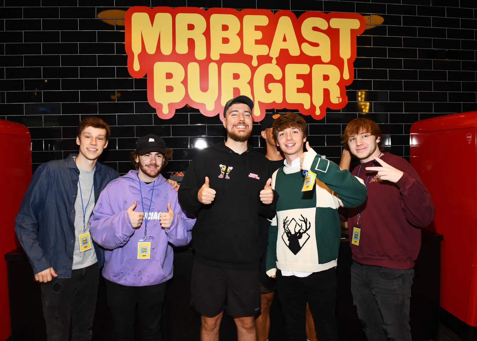 Jimmy Donaldson, or MrBeast, smiles and poses with other influencers in front of branding for his burger chain.