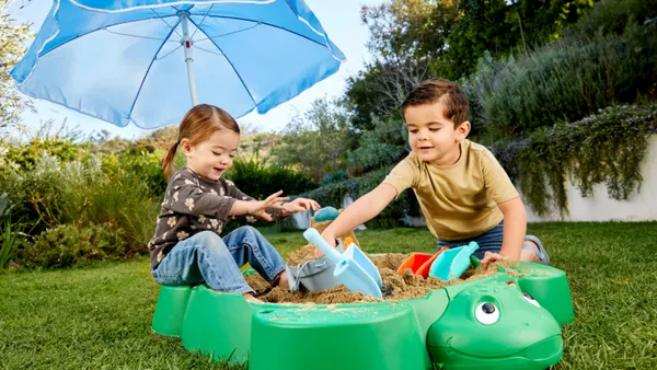 Children play in a Little Tikes turtle sandbox.