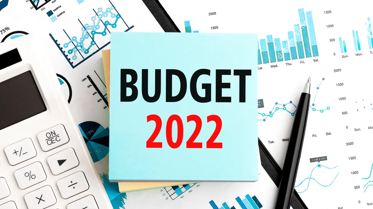 Text BUDGET 2022 on stickers. Pen and calculator on clipboard with charts, documents and graphs. Business plan. Top view.