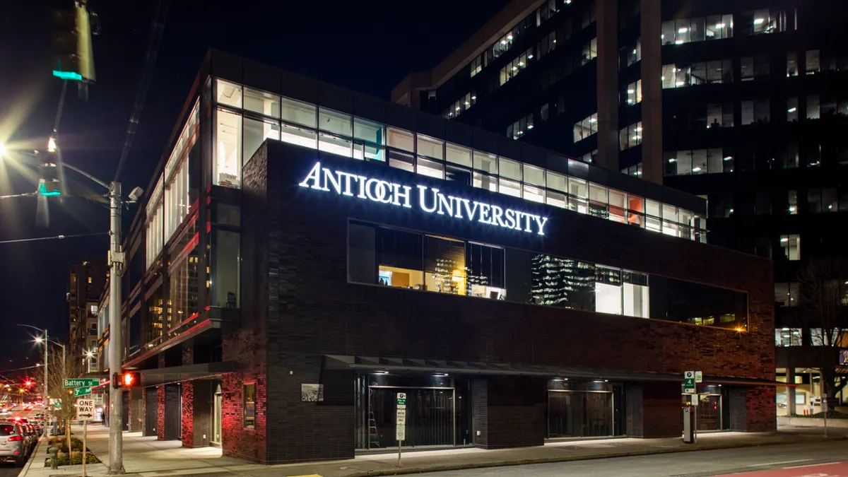 Building at night with illuminated sign and lights from street lamps and traffic.
