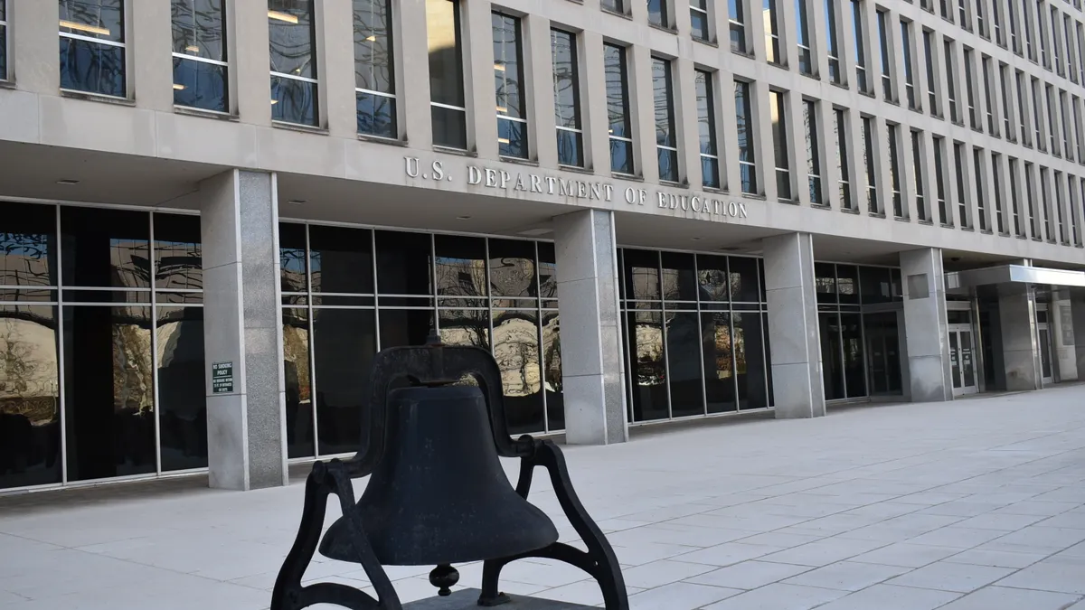 A large metal bell sits in the courtyard in front of the U.S. Department of Education building.