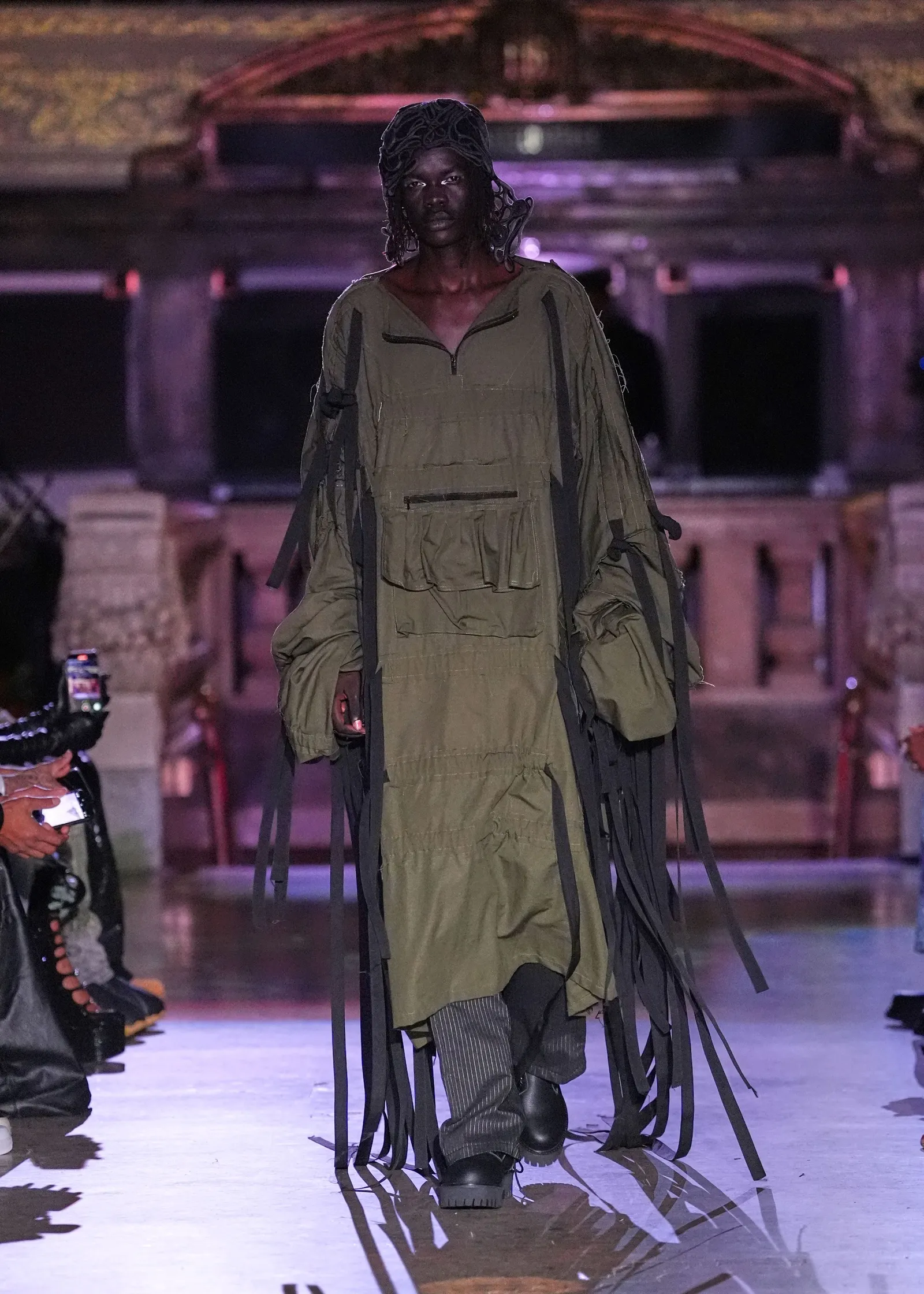 A model in an olive green outfit walks the runway.