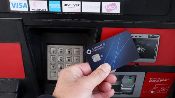 Hand holding Saphire Preferred credit card reaches to tap the card at a fuel pump.