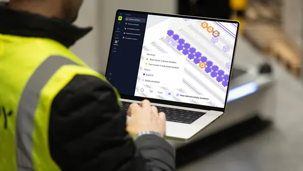 Warehouse worker using a laptop displaying 3D warehouse optimization software.