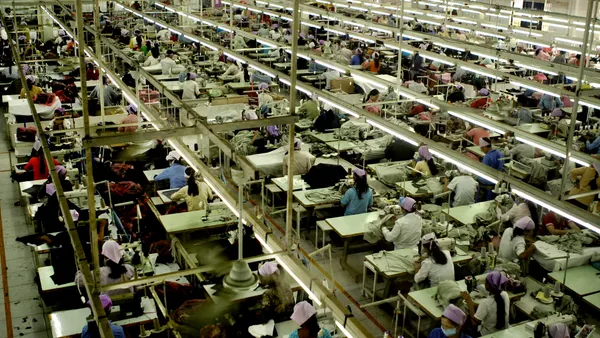 An overhead view of a garment factory floor shows workers using sewing machines.