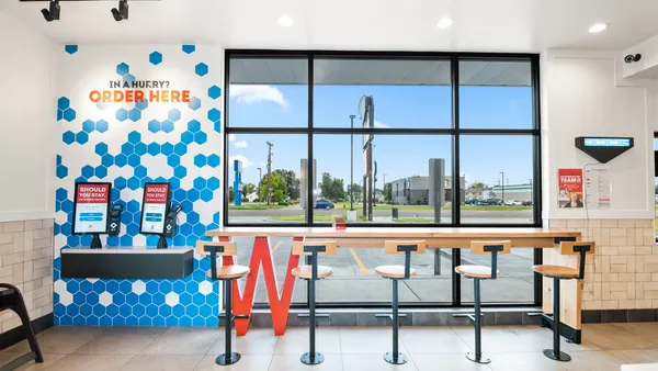 An interior photograph of a Wendy's restaurant with digital kiosks for ordering.