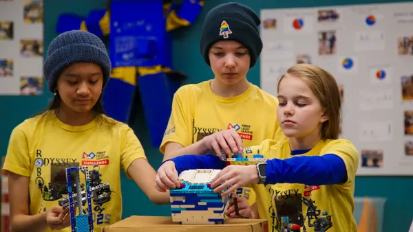 Three students work on a robotics project in a room