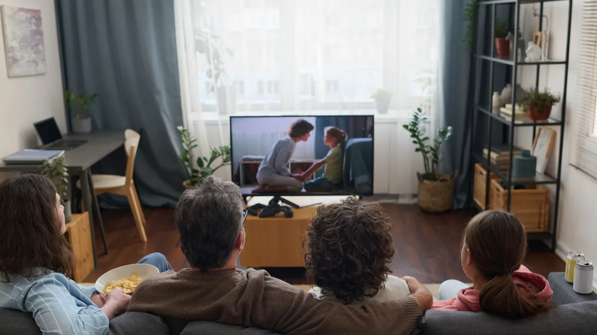 A family sits together watching TV.